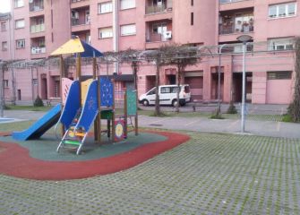 Coches en parque infantil y plaza peatonal