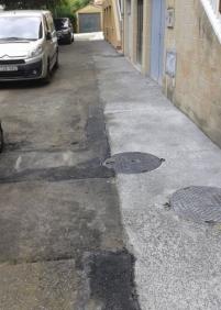 Calle mal asfaltada tras obras en Río Deva 17, 19  y 21